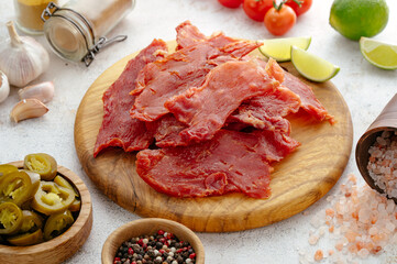 jerky on a wooden board with herbs and spices