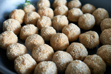 Raw meatballs in a frying pan, close-up.
