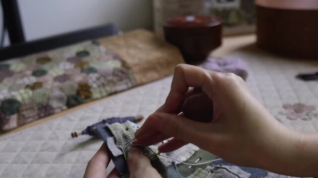 Hands hand sewing a decorative textile patchwork