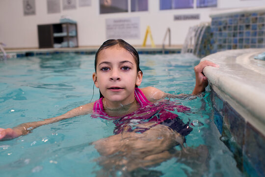 Girl rests at pool edge with water behind her