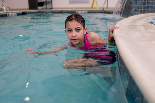 Girl holds onto pool edge during swimming practice