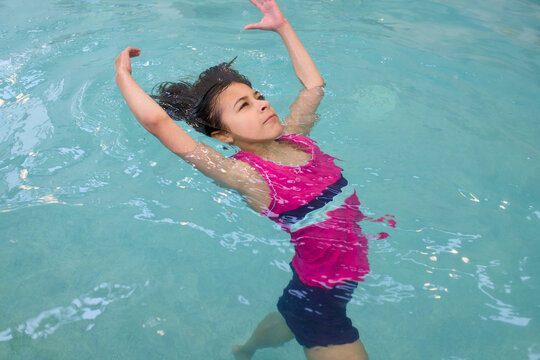 Young girl floats on her back in swimming pool
