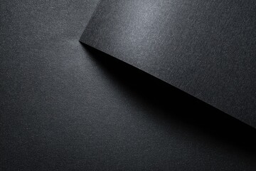 Abstract close-up of two sheets of dark gray textured paper, overlapping at an angle