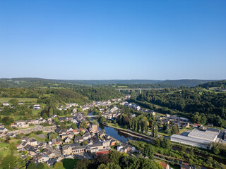 Fototapeta premium Sougne-Remouchamps, Aywaille, Liege, Wallonie, Belgium, August 10, 2025, An aerial view beautifully captures a tranquil village situated by a gentle river, elegantly enveloped by lush greenery