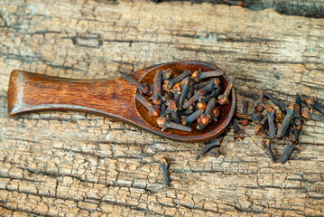 dried cloves in the wooden spoon on wooden background