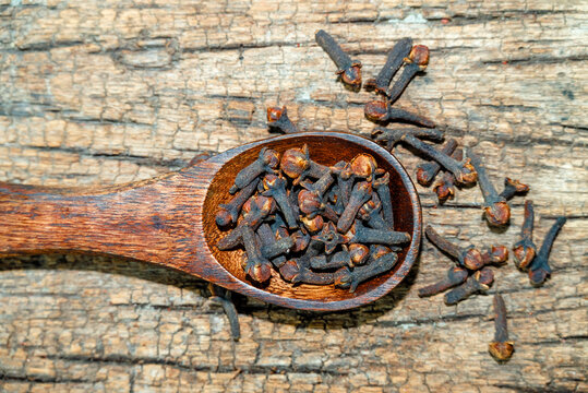 dried cloves in the wooden spoon on wooden background