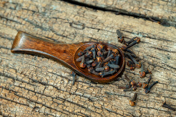 dried cloves in the wooden spoon on wooden background