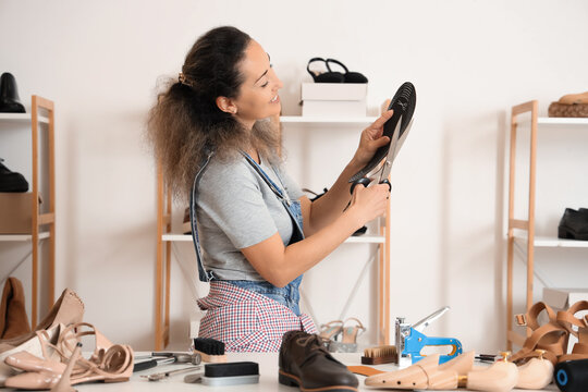 Female shoemaker cutting insole in workshop
