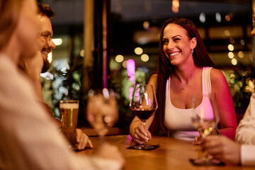 Friends Sharing Drinks and Laughter at a Cozy Night Restaurant Setting