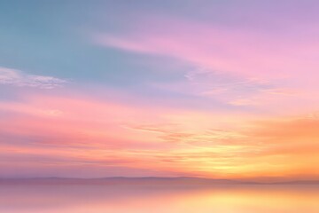 A pastel sky blends pink yellow and blue meeting a hazy horizon over a serene body of water