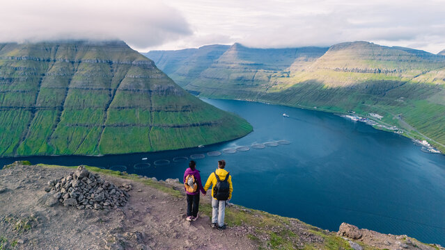 Breathtaking view of the Faroe Islands with hikers overlooking serene fjords and lush landscapes