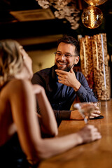 Smiling Couple Enjoying a Conversation at an Elegant Bar in Warm Lighting