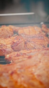 Juicy pork ribs sizzling on hot grill, golden brown crust forming during outdoor barbecue cooking with smoky aroma.