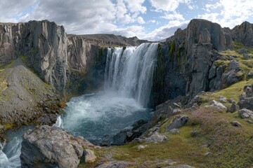 Majestic waterfall cascading into a rocky basin, surrounded by rugged mountains