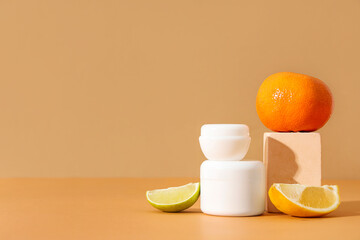 Composition with jars of cosmetic products, citrus fruits and plaster stand on beige background