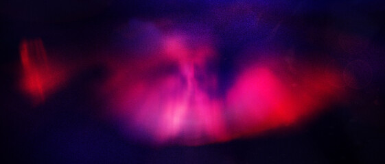 Abstract blurred light composition with red, pink, blue, and dark tones creating a soft glowing effectwith and background grainy.