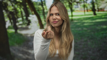 Obraz premium Woman claps her bare hands with open mouth and wide eyes expression in sunlit green park; surprise joy contentment.