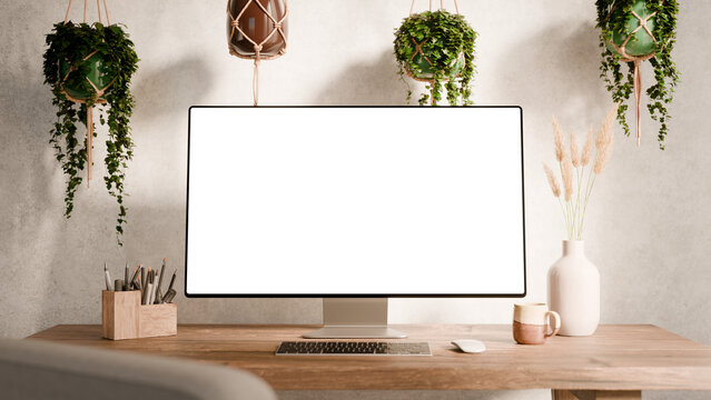 Computer monitor with blank screen mockup on a wooden desk - modern workspace in boho style surrounded by hanging plants and minimalist decor - Front Side Wide Perspective