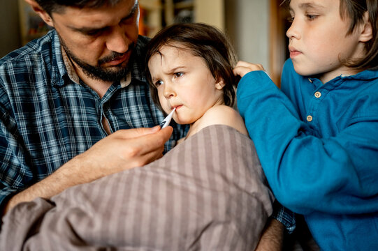 Father measuring temperature of sick son at home