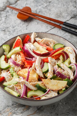Dak Nangchae Korean chicken salad with cucumber and apple tossed with tangy sesame mustard dressing closeup on the plate on the table. Vertical