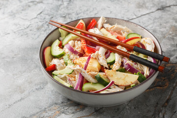 Chicken salad with cucumber, apple, red onion, bell pepper and sesame-mustard dressing close-up in a bowl on the table. Horizontal