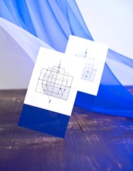 Two cards with graphic designs on a wooden surface with fabric