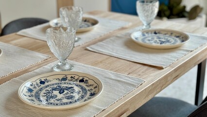 Elegant Table Setting with Blue and White Plates and Crystal Glasses in a Cozy Dining Room