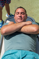 Man relaxing on a bench with arms crossed, child standing nearby