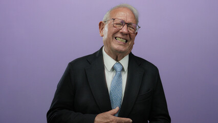 Senior man in a business suit over isolated purple background shows discomfort with hand on stomach, expressing possible pain or discomfort, facing slight distress.