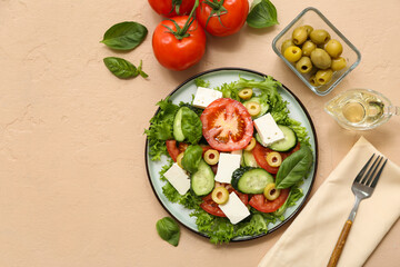 Plate of fresh vegetable salad with fork and ingredients on beige background