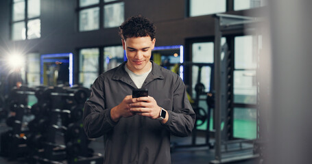 Fototapeta premium Texting, man and happy with smartphone, gym and communication with contact on social media and chat. Online, athlete and person with mobile on break, fitness and message with tech in health club