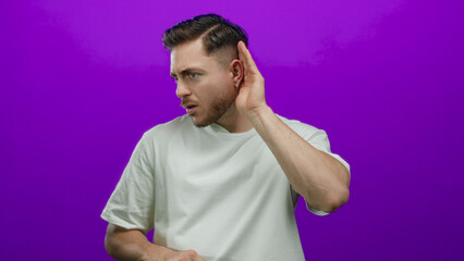 Young man with beard listening intently on a vivid purple background, highlighting focus and curiosity through expressive gestures and isolated environment.