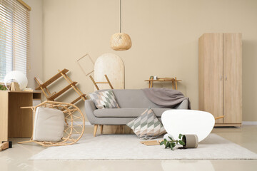 Obraz premium Interior of damaged living room with sofa and overturned furniture after earthquake