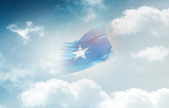Somalia flag waving light background hidden in the sky.