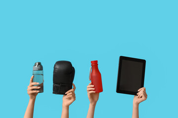 Female hands with water bottles, boxing glove and tablet computer on blue background. Prostate...