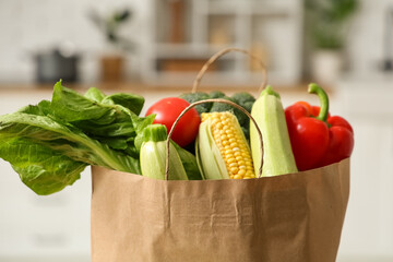 Shopping bag with different fresh vegetables in kitchen, closeup
