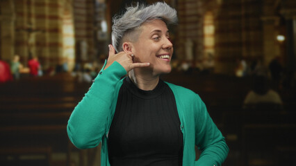 Woman hand phone gesture inside ornate church building interior with wooden pews in focus; friendly...
