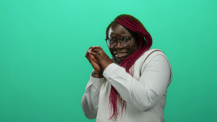 Woman with pink braids and glasses poses nervously against an isolated green background wall...
