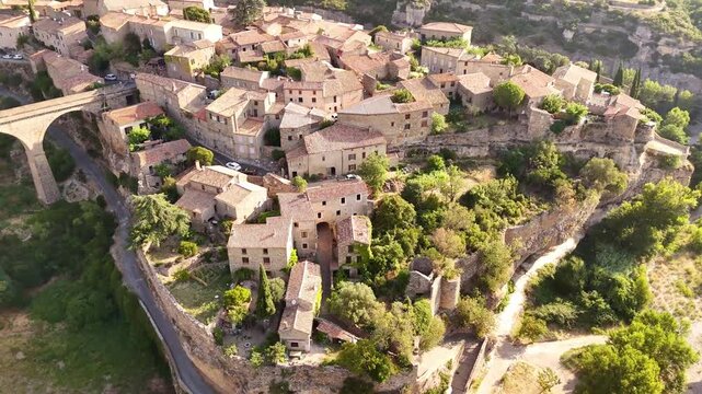 Aerial view of Minerve village with its compact stone houses and red-tiled roofs nestled amidst the rugged, sun-drenched landscape, Minerve, Occitanie, France.