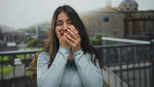 Young woman in rome stands surprised at ancient ruins background, expressing excitement and joy, wearing casual attire, capturing modern travel emotions.