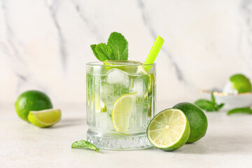 Glass of fresh Mojito cocktail with limes and mint on white background