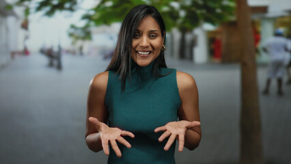 Young woman smiling outdoors on a street with trees in the background during daytime.