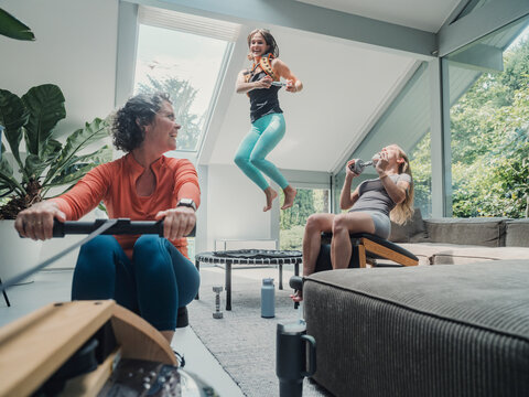 Family enjoying home workout with rowing, trampoline and relaxation