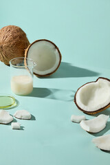 Fresh coconuts with glass of milk on aqua background, styled for wellness, tropical spa, and beauty treatment concepts.