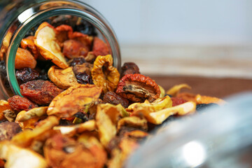Scattered dried fruit from a glass jar on a rustic surface