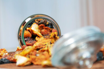 Tipped glass jar with assorted dried fruits spilling out
