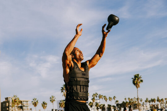 Mature man catching kettlebell under sky