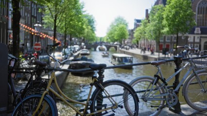 Obraz premium Bicycles parked along amsterdam canal with blurred background showcasing trees and boats, capturing essence of netherlands urban scenery.