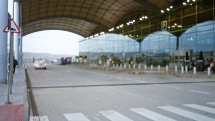 Blurred view of terminal 1 exterior at an airport with bokeh lights and defocused cars under a vast roof, capturing the essence of travel and transportation.