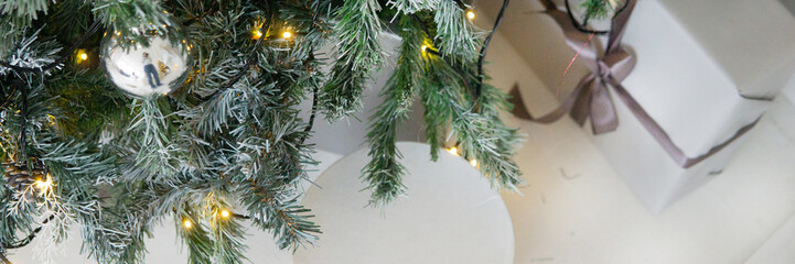 Designer Christmas tree decoration with light decorations. The concept of celebrating New Year and Christmas. Gifts in craft packaging under the Christmas tree.